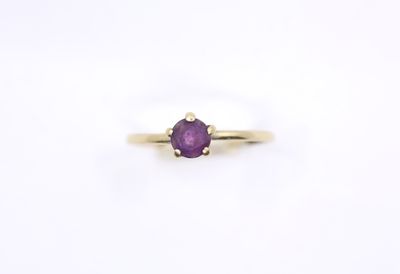 a close up of a yellow gold ring with a purple stone