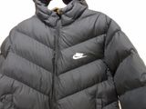 the jacket is black and has a white nike logo on it