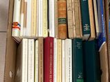 une boîte remplie de livres posée par terre à côté des toilettes