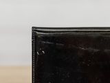 someone is holding a black wallet on a table with a white wall in the background