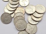 a close up of a pile of silver coins on a white surface