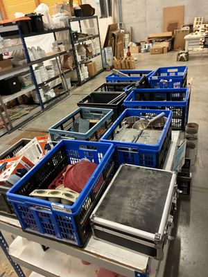 Des cartons contenant des articles variés sont alignés sur un chariot dans un entrepôt.