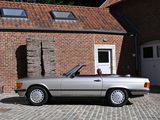 a silver convertible car parked in front of a brick building