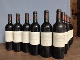 six bottles of wine are lined up on a wooden table