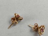 a pair of gold earrings with pink stones on a white surface