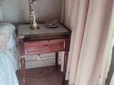 une petite table sur laquelle est posée une lampe, à côté d'un lit