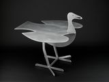 a metal bird that is sitting on a metal stand