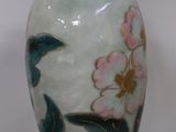 a vase with a flower design on it sitting on a table