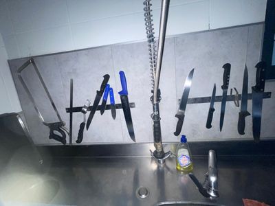 de nombreux couteaux accrochés au mur au-dessus d'un évier