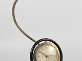 une image représentant une horloge posée sur un socle et surmontée d'une lampe