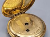 a gold pocket watch sitting on a table with a keychain