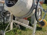 a cement mixer sitting on the grass in front of a house