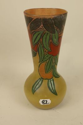 a yellow vase with oranges and leaves painted on it