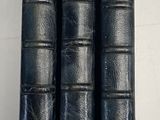 trois livres en cuir noir posés sur une table blanche