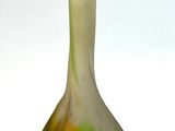 un vase vert et jaune posé sur une surface blanche
