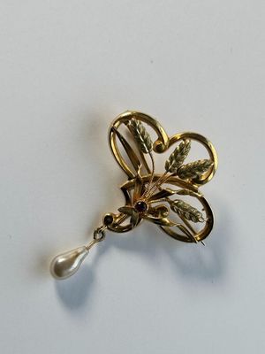 a close up of a brooch with a pearl in it