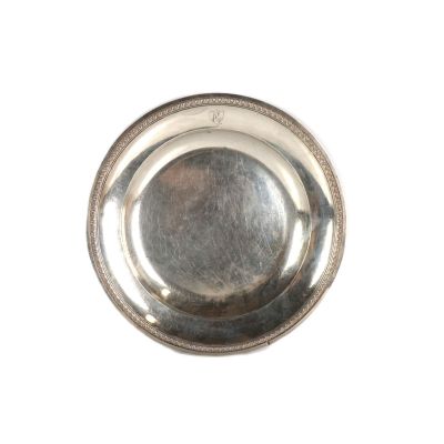 une assiette en argent posée sur un plateau blanc, bordée d'argent