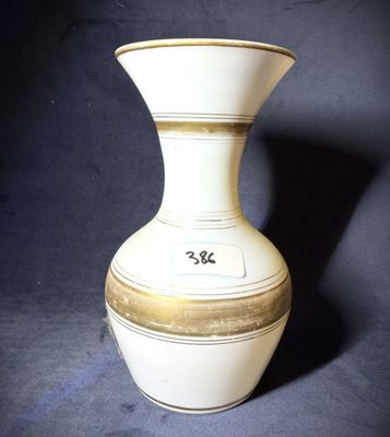 un vase blanc et doré posé sur une surface noire