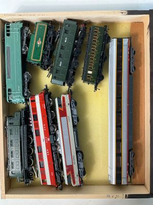 plein de petits trains miniatures dans une boîte posée sur la table