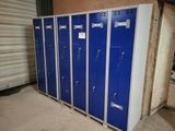 Plusieurs casiers bleus sont alignés les uns à côté des autres dans un garage
