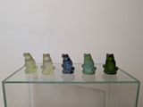 four frogs sitting on top of a glass shelf
