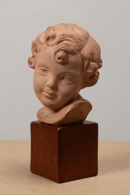 une petite statue représentant un enfant, posée sur un socle en bois