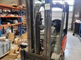 un chariot élévateur dans un entrepôt où il y a beaucoup de cartons par terre