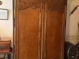 une grande armoire en bois dans une pièce où se trouvent une table et une chaise