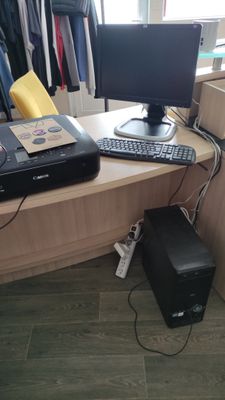 a computer desk with a printer, keyboard, and monitor on it
