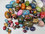 a pile of colorful painted eggs on a white table