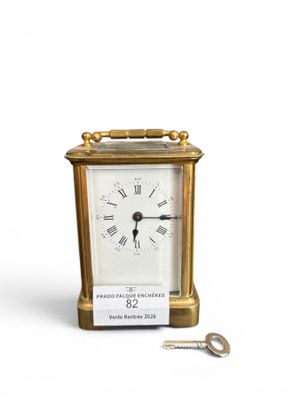 une petite horloge en or avec une clé sur le côté