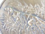 a silver coin with a dog and a bird on it
