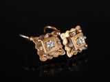 une paire de boucles d'oreilles en or et diamants sur une surface noire