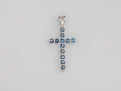 a cross pendant with blue crystals on a white background