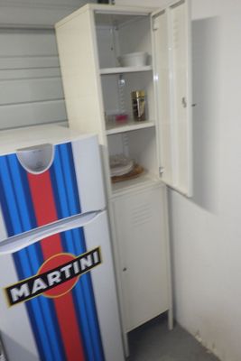 un réfrigérateur dans un coin d'une pièce, dont la porte est rayée de bleu et de rouge