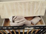 a baby crib with a mattress and a blanket in it