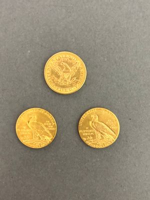three different types of gold coins on a gray surface