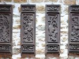 trois plaques en bois fixées au mur d'un bâtiment en pierre