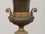 a bronze vase on a pedestal with a clock on it