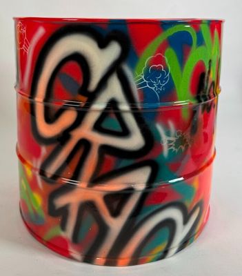 un récipient rouge orné de graffitis, posé sur une surface blanche