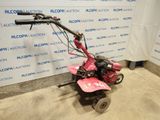an image of a small pink lawn mower parked in a garage