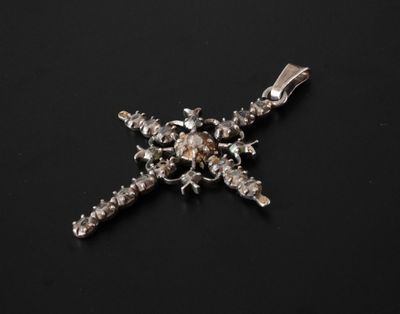 un gros plan d'une croix en argent sur une surface noire
