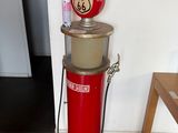 a red gas pump sitting on the floor next to a table