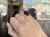 woman ' s hand holding a red and white ring in front of a window