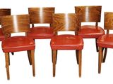 six chaises en bois dont les assises sont recouvertes de cuir rouge, sur fond blanc