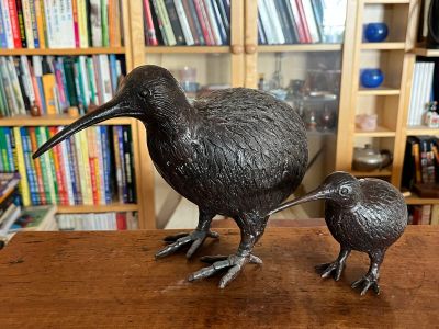 une statue représentant deux oiseaux, posée sur une table devant une bibliothèque