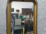 a mirror hanging on the wall with a gold frame