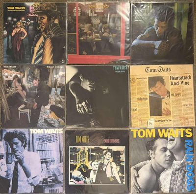 various album covers on a wall with a man smoking a cigarette