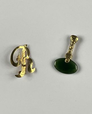 two pieces of gold and green jewelry on a white surface