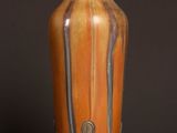 an orange vase sitting on top of a wooden table next to a black wall
